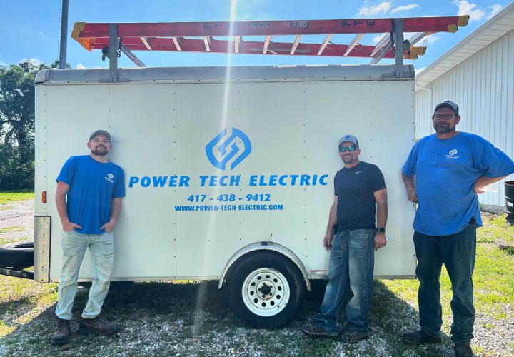 Three electricians standing in front of a branded work trailer, representing the skilled team behind reliable electrical services.